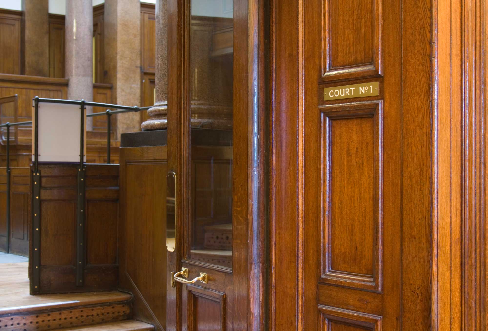 Image of entrance to Court No. 1 with heavy wood paneling and glass paned doors.